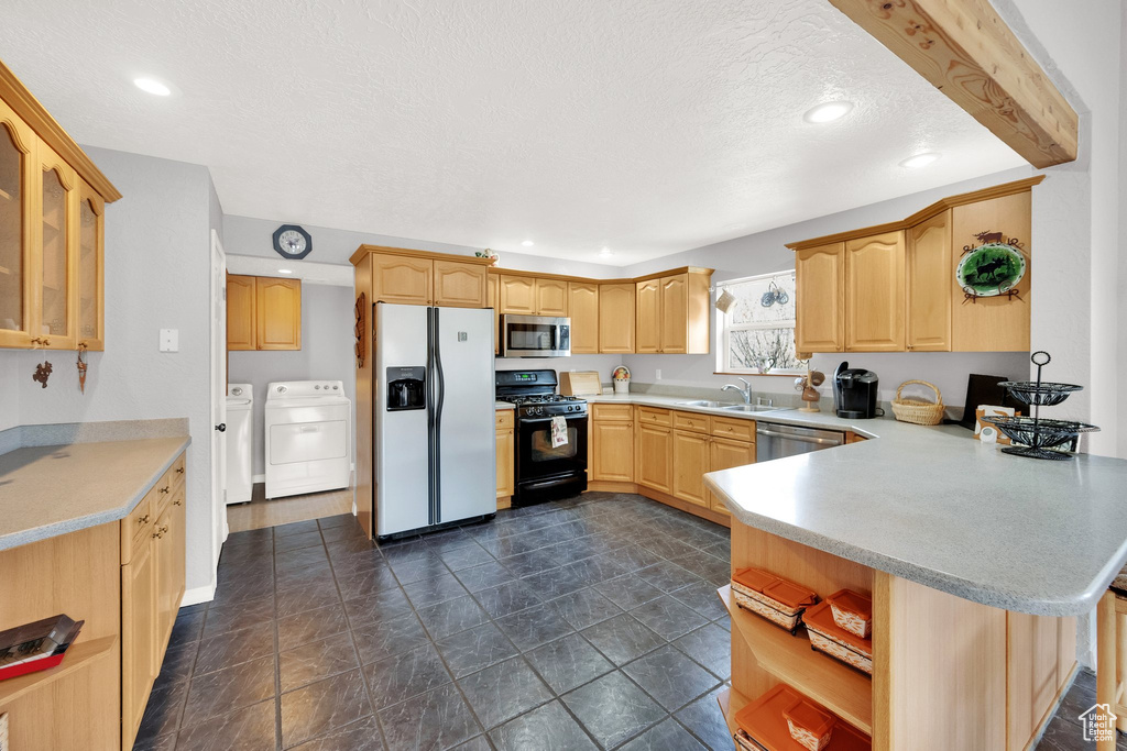 Kitchen featuring open shelves, a textured ceiling, stainless steel appliances, a peninsula, and washing machine and dryer