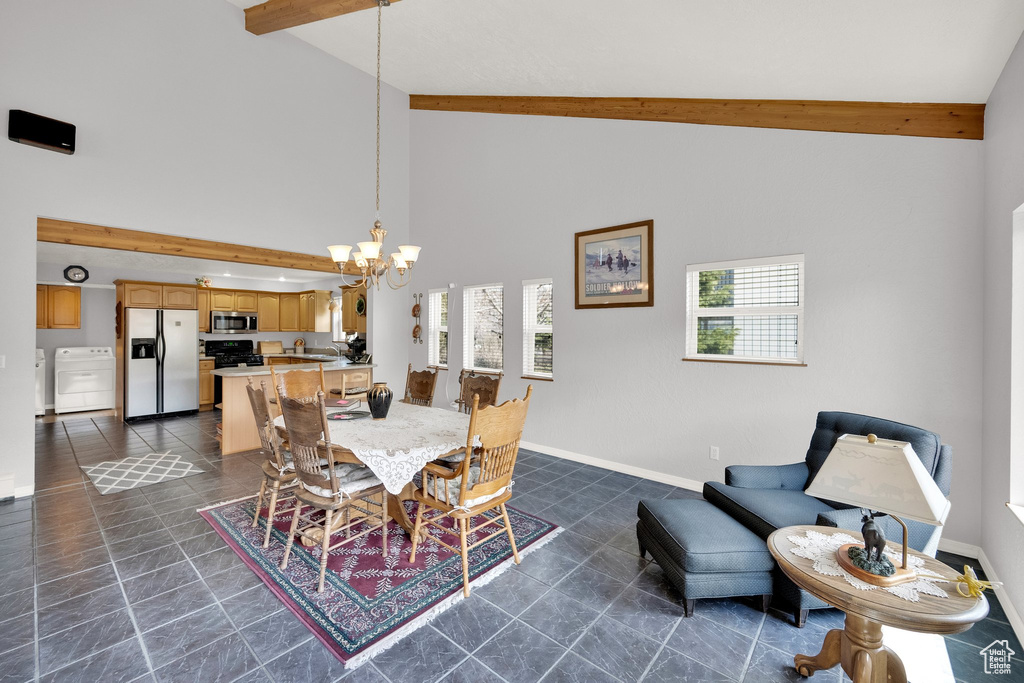 Dining room with beam ceiling, baseboards, high vaulted ceiling, washer and clothes dryer, and a notable chandelier