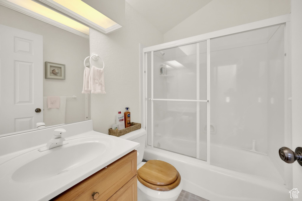 Bathroom with vanity, bath / shower combo with glass door, toilet, and lofted ceiling