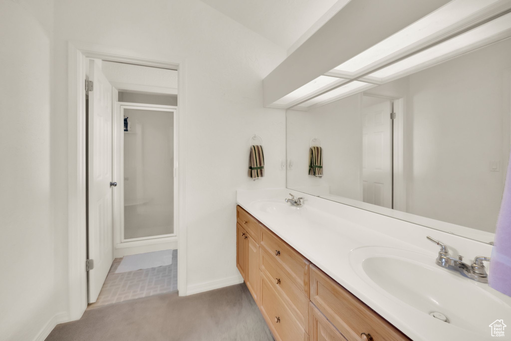 Bathroom featuring double vanity, a sink, baseboards, and a shower stall