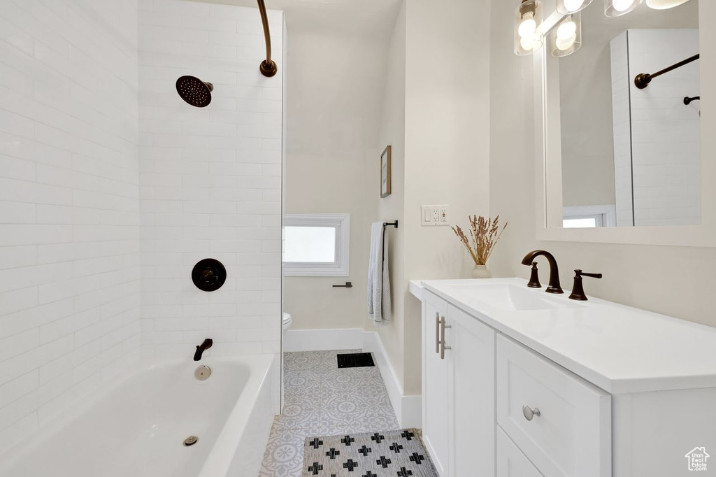 Bathroom featuring toilet, vanity, baseboards, and bathtub / shower combination