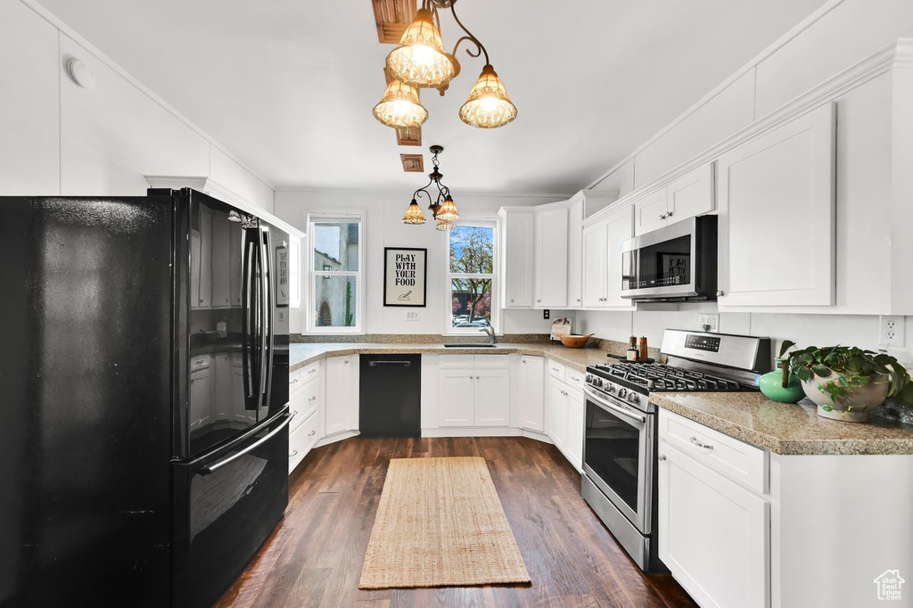 Kitchen with dark wood-type flooring, a notable chandelier, white cabinetry, and black appliances