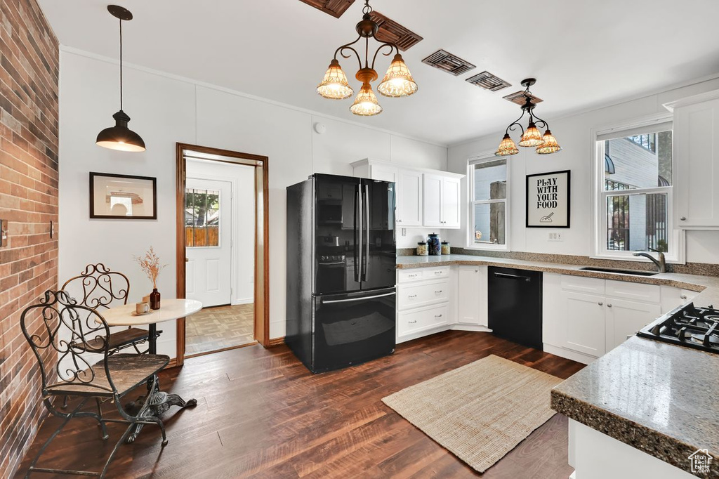 Kitchen with a notable chandelier, dark wood-style floors, white cabinets, black appliances, and a sink