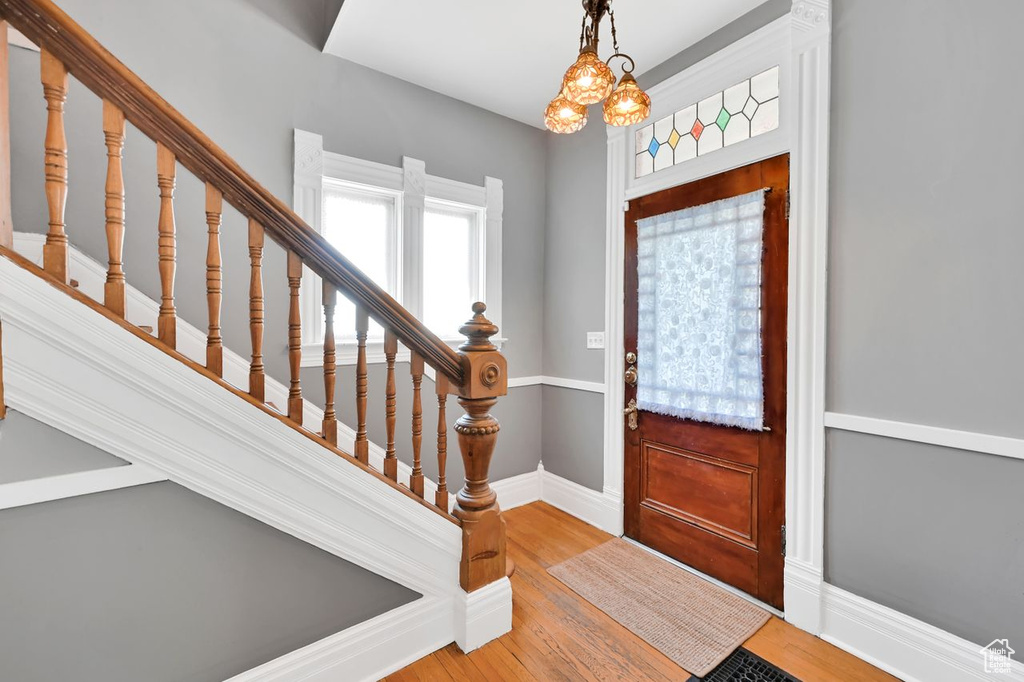 Entrance foyer featuring a chandelier, light wood finished floors, baseboards, and stairs