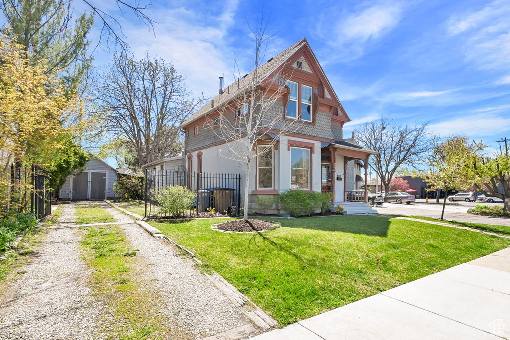 Traditional-style house featuring an outbuilding, a storage unit, a front yard, fence, and driveway