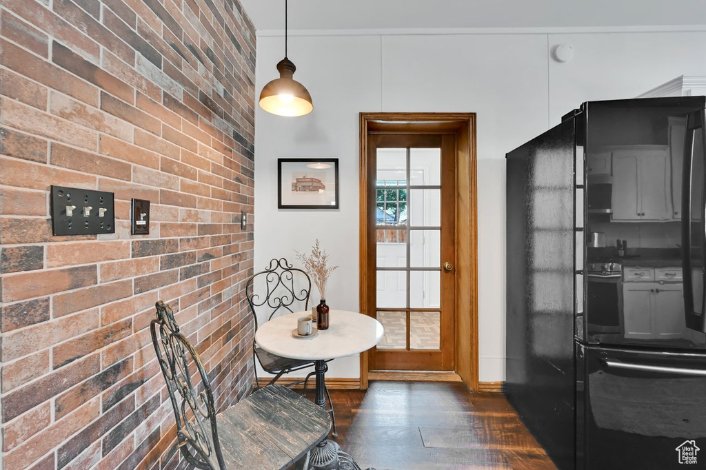 Interior space featuring brick wall, baseboards, and dark wood-style floors
