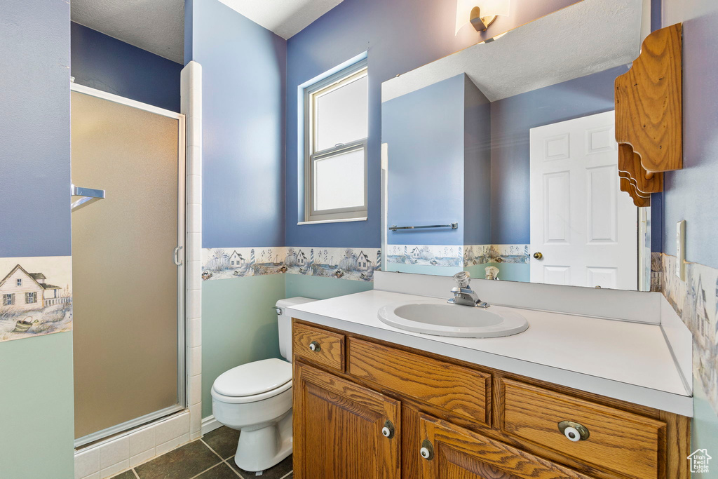 Full bathroom featuring toilet, a stall shower, vanity, and tile patterned flooring