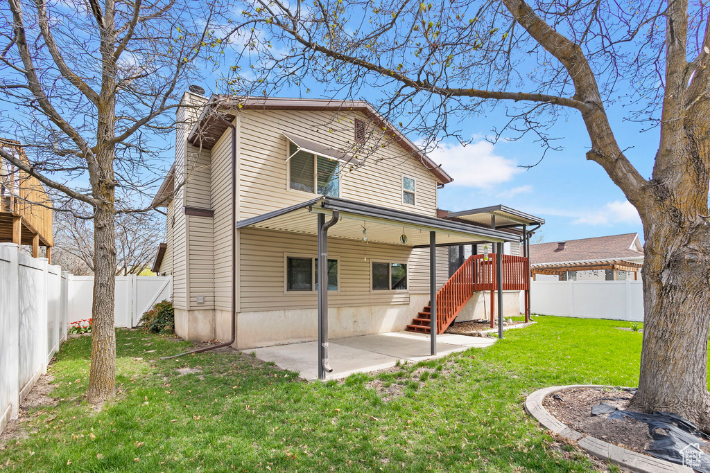Rear view of property with a yard, a fenced backyard, a patio, and a chimney