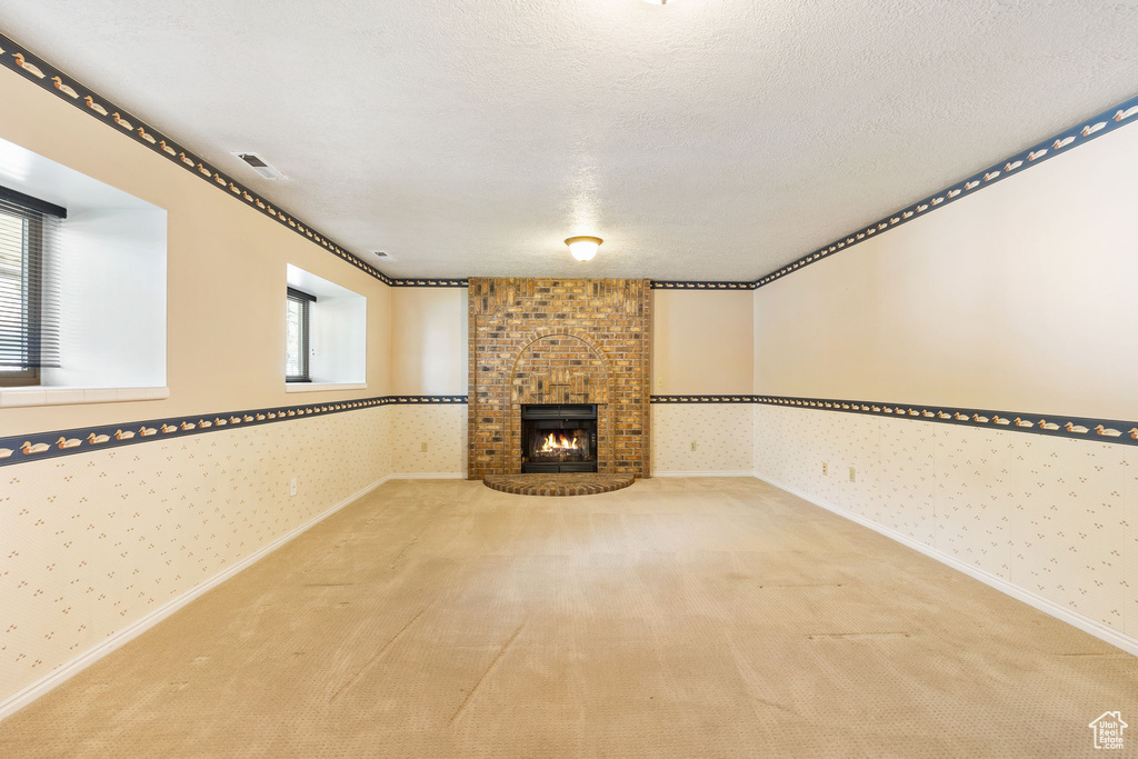 Unfurnished living room with wallpapered walls, carpet flooring, and visible vents