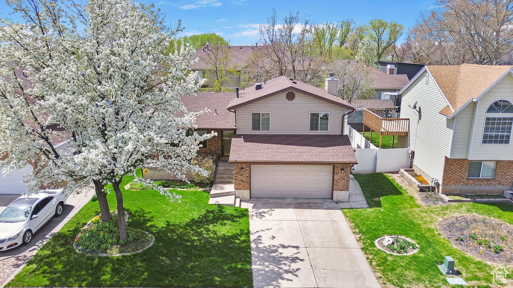 Traditional-style home with a garage, roof with shingles, a front yard, brick siding, and driveway