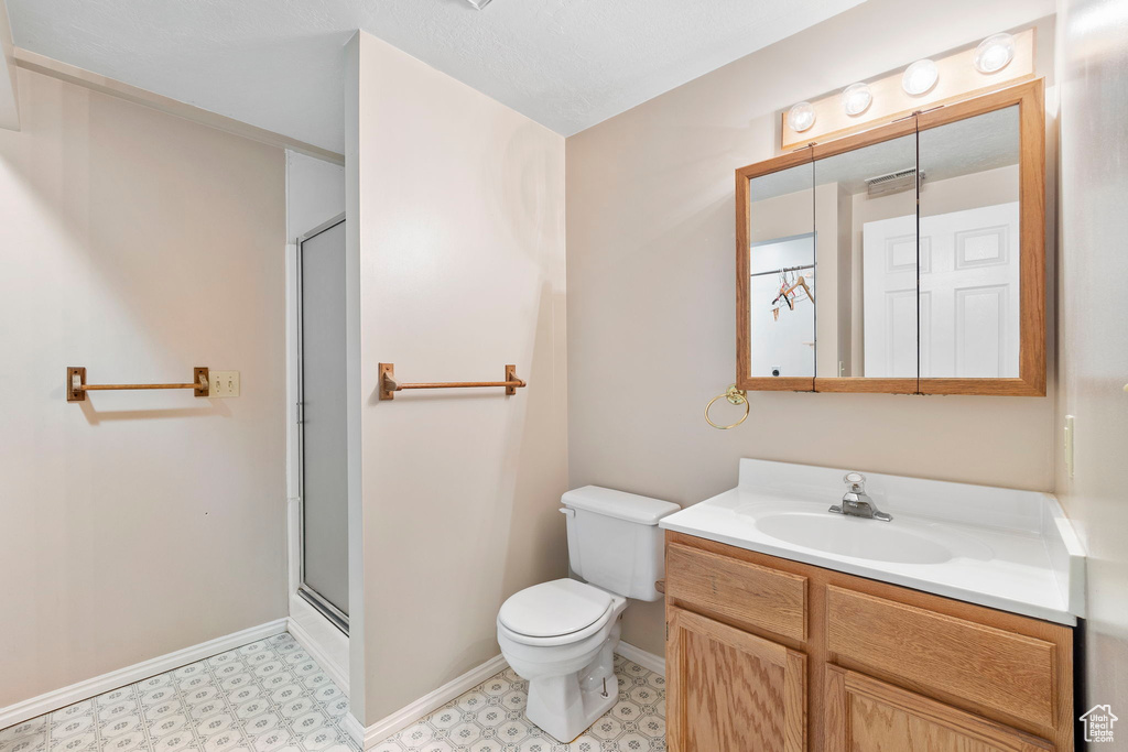 Full bath with vanity, a shower with door, toilet, tile patterned floors, and baseboards