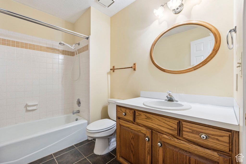 Bathroom featuring toilet, tile patterned floors, vanity, and washtub / shower combination