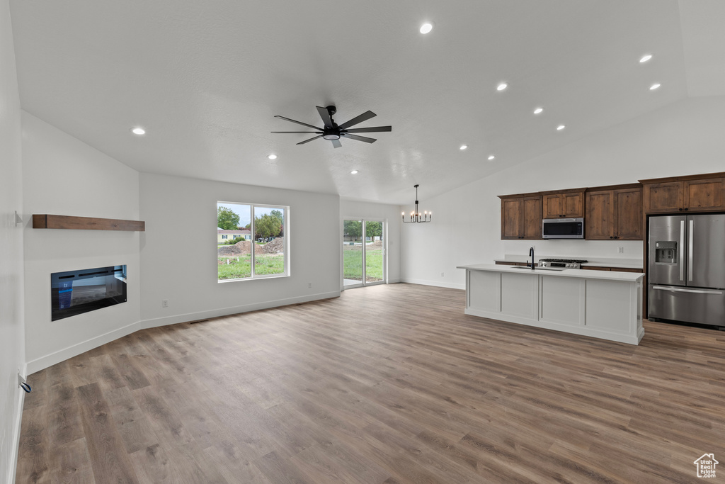 Kitchen featuring appliances with stainless steel finishes, open floor plan, vaulted ceiling, a chandelier, and recessed lighting