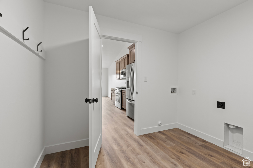 Clothes washing area featuring hookup for an electric dryer, washer hookup, light wood finished floors, and baseboards
