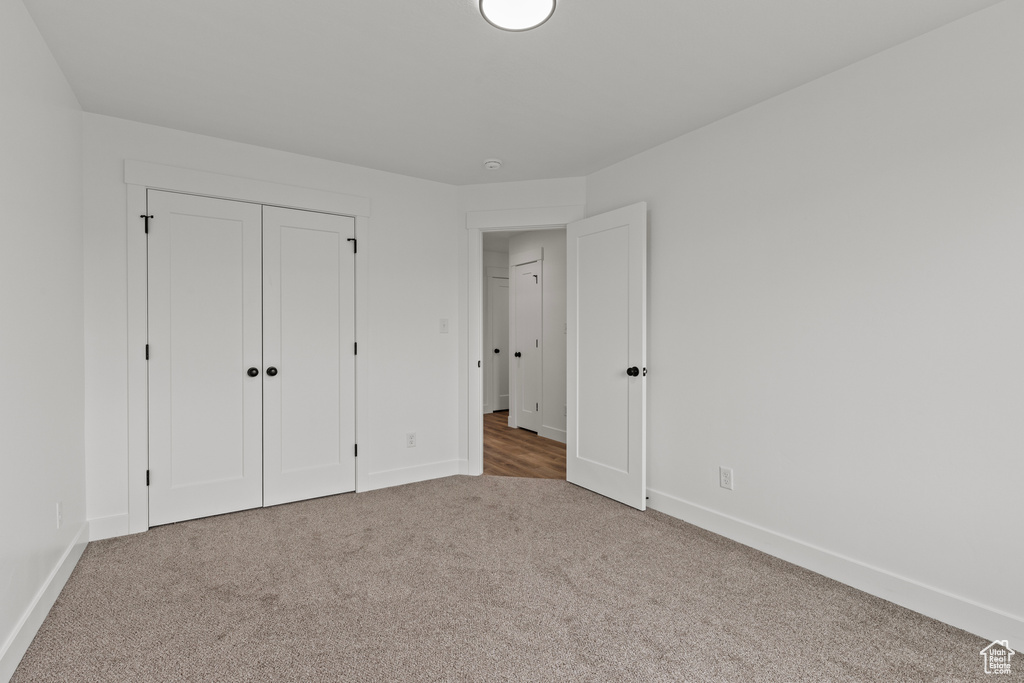 Unfurnished bedroom with carpet floors, baseboards, and a closet