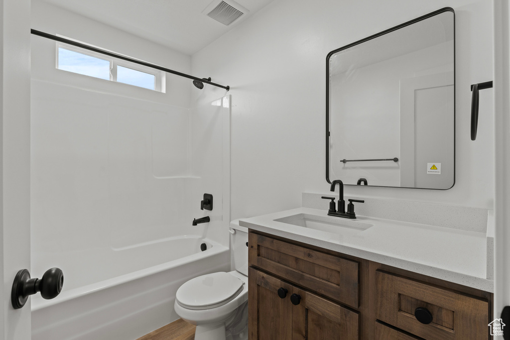 Bathroom featuring vanity, toilet, shower / tub combination, and wood finished floors