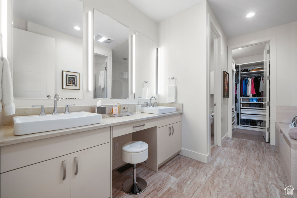 Full bathroom with a sink, a washtub, double vanity, and a spacious closet