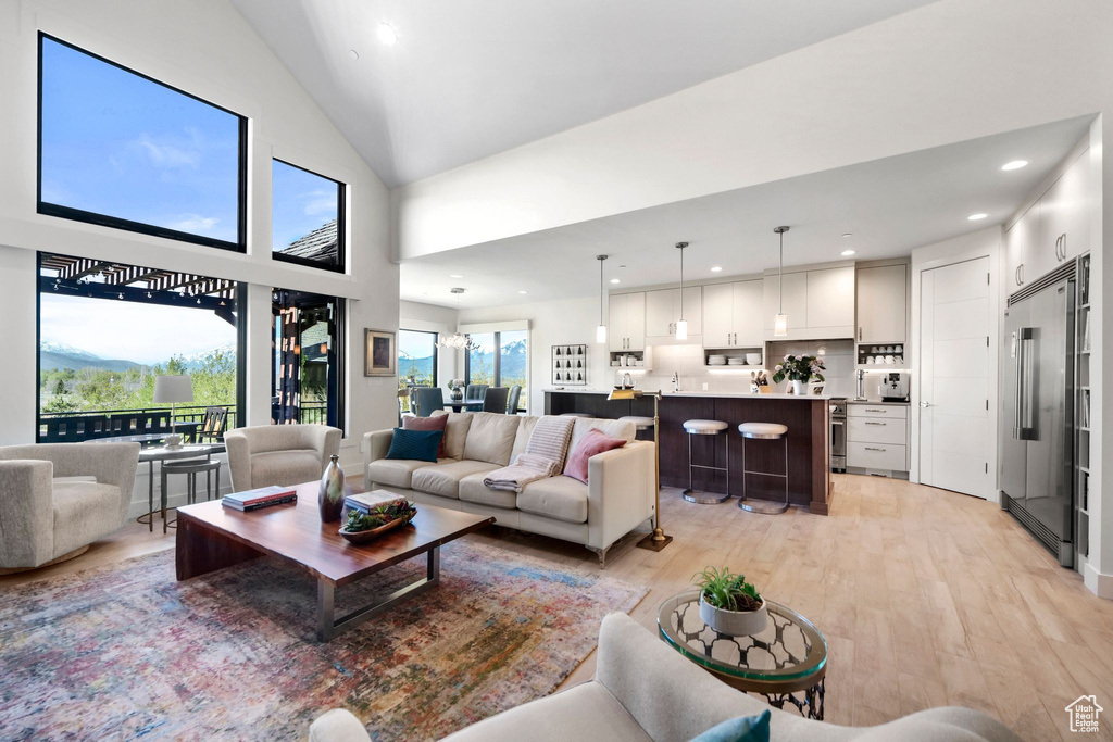 Living room with recessed lighting, lofted ceiling, and light wood finished floors