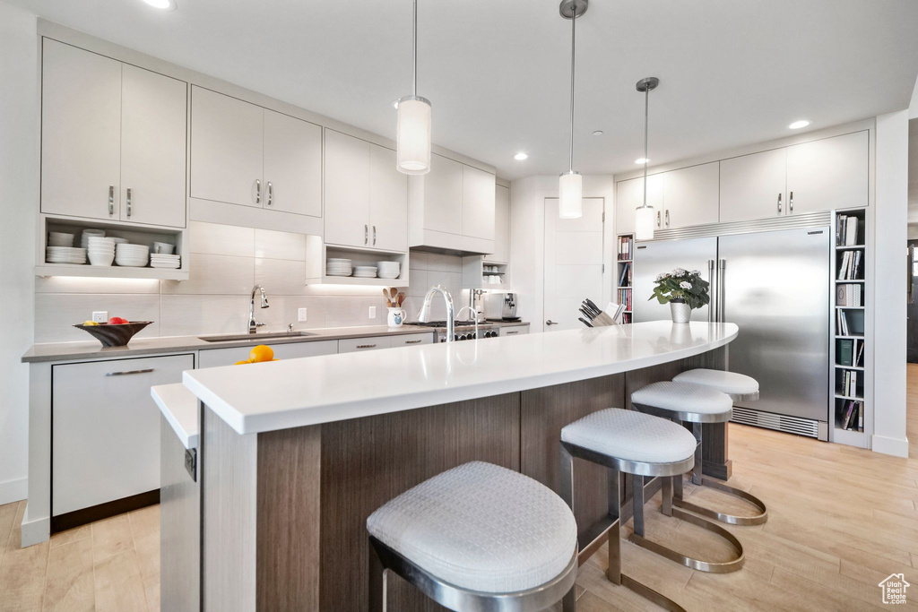 Kitchen with a sink, light wood-style flooring, recessed lighting, tasteful backsplash, and stainless steel built in refrigerator