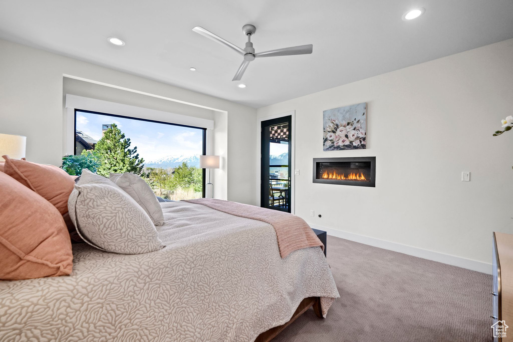 Bedroom featuring a glass covered fireplace, carpet floors, baseboards, and recessed lighting