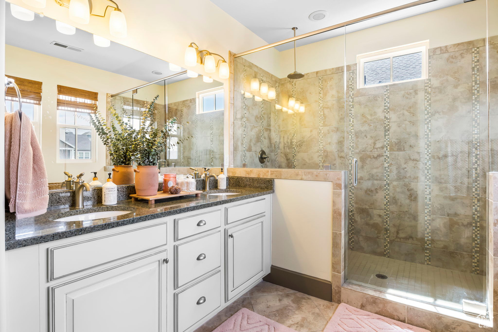 Full bathroom with a stall shower, double vanity, a sink, and visible vents