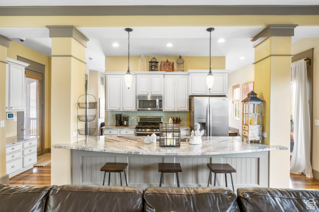 Kitchen with backsplash, appliances with stainless steel finishes, a breakfast bar, and light stone counters