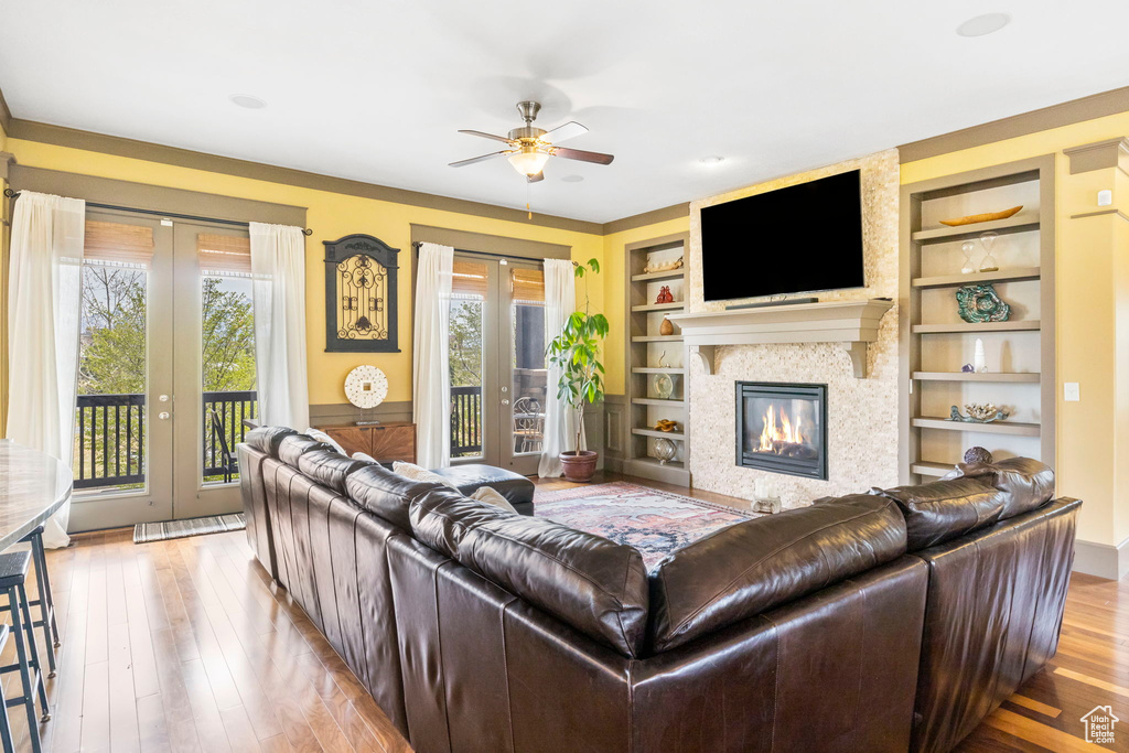 Living room with built in shelves, french doors, wood-type flooring, and ceiling fan