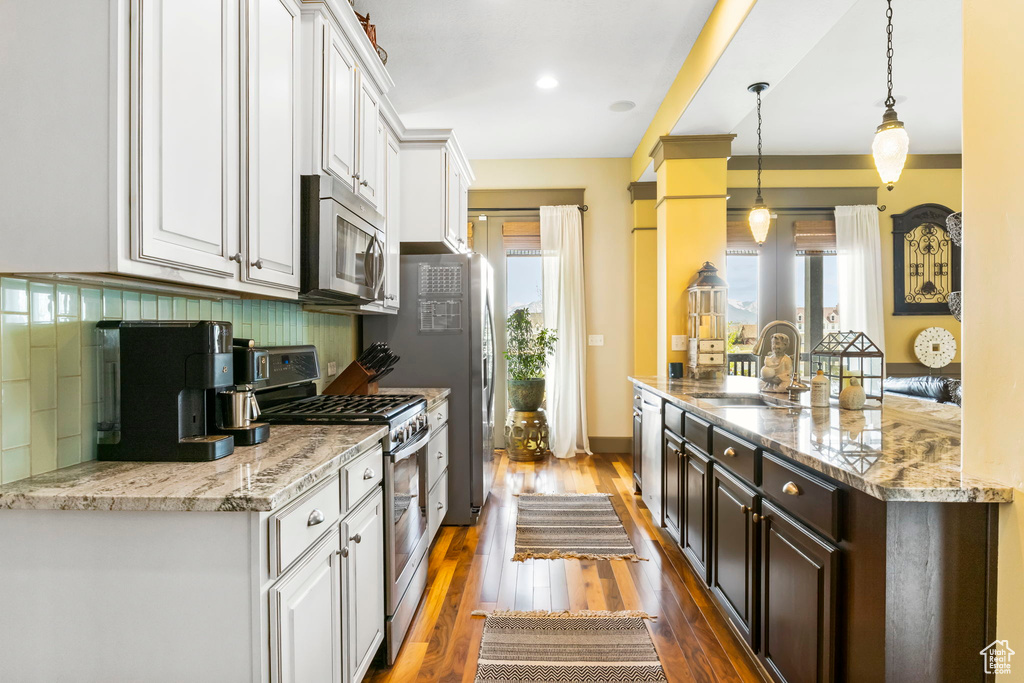 Kitchen featuring appliances with stainless steel finishes, a sink, white cabinetry, and a healthy amount of sunlight