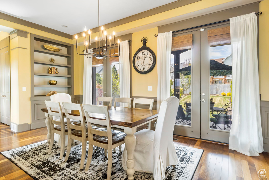 Dining room with french doors, built in features, a notable chandelier, and light wood-style floors