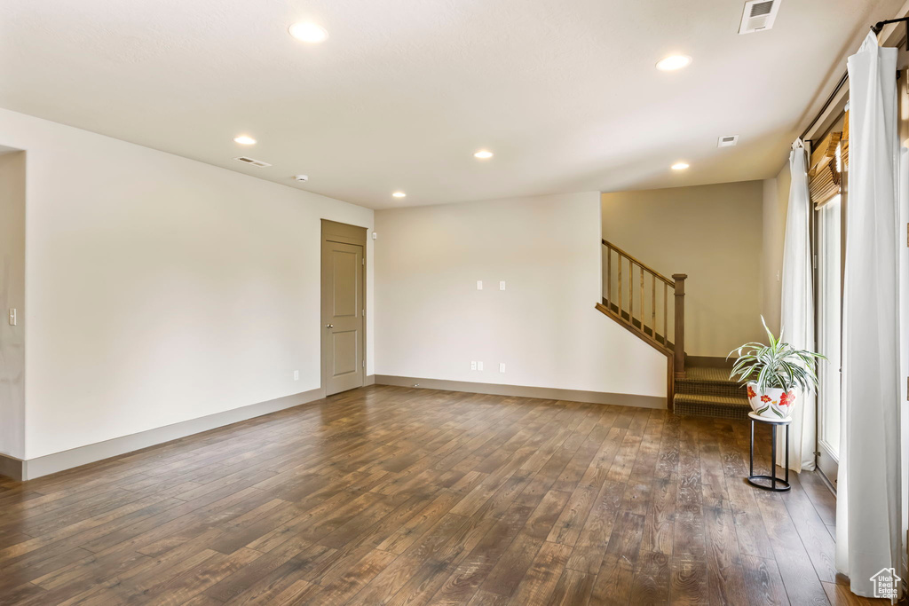 Unfurnished room featuring visible vents, baseboards, dark wood-style flooring, stairway, and recessed lighting