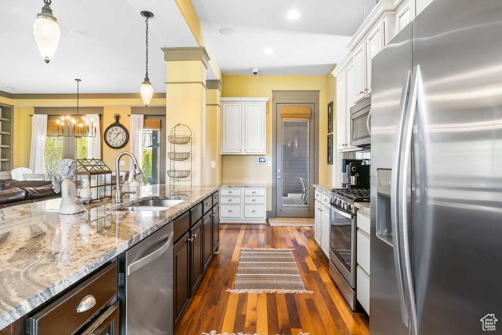 Kitchen with a notable chandelier, dark brown cabinets, white cabinets, appliances with stainless steel finishes, and a sink