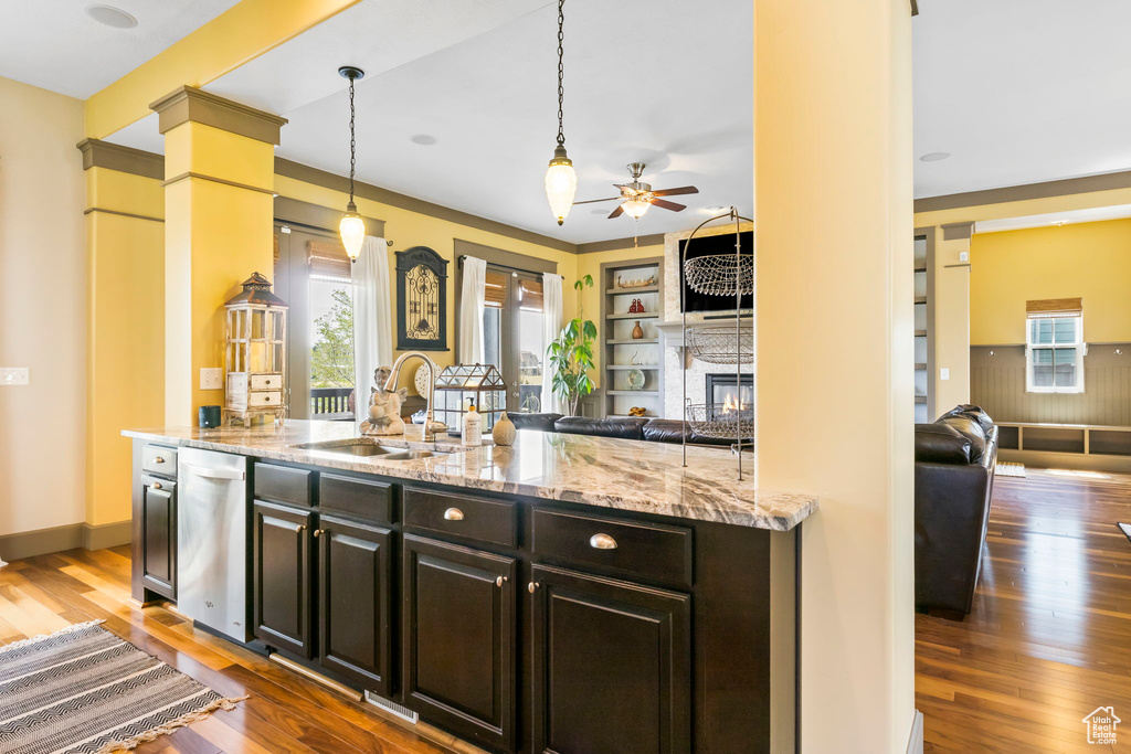 Kitchen with open floor plan, ceiling fan, a sink, and a glass covered fireplace