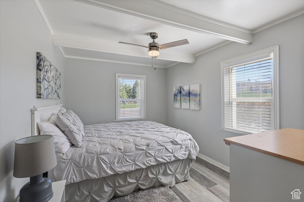 Bedroom featuring crown molding, beam ceiling, baseboards, and wood finished floors