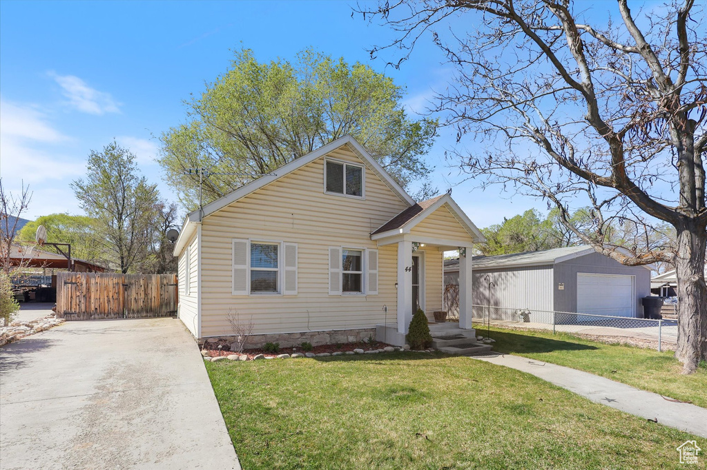 Bungalow-style house with a front yard, fence, and concrete driveway