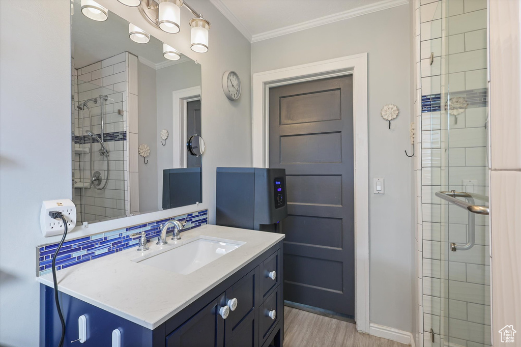 Full bathroom featuring a stall shower, wood finished floors, crown molding, and baseboards