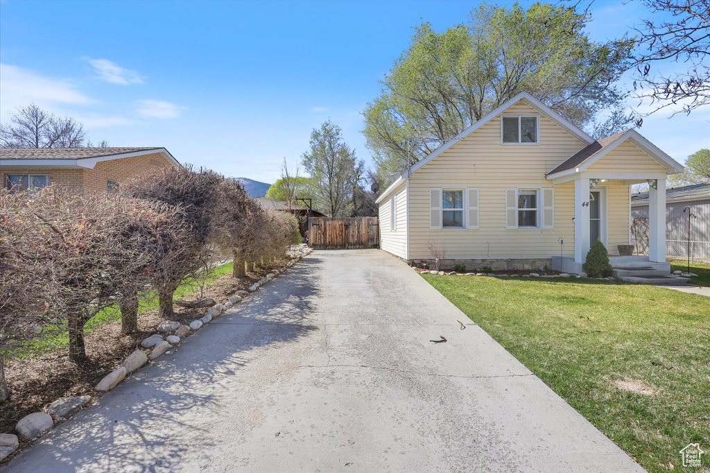 Bungalow-style home featuring driveway, fence, and a front lawn