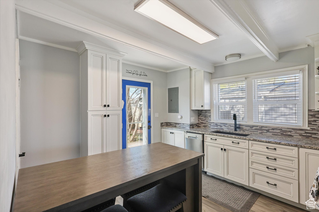 Kitchen featuring light wood-type flooring, a sink, backsplash, and white cabinets