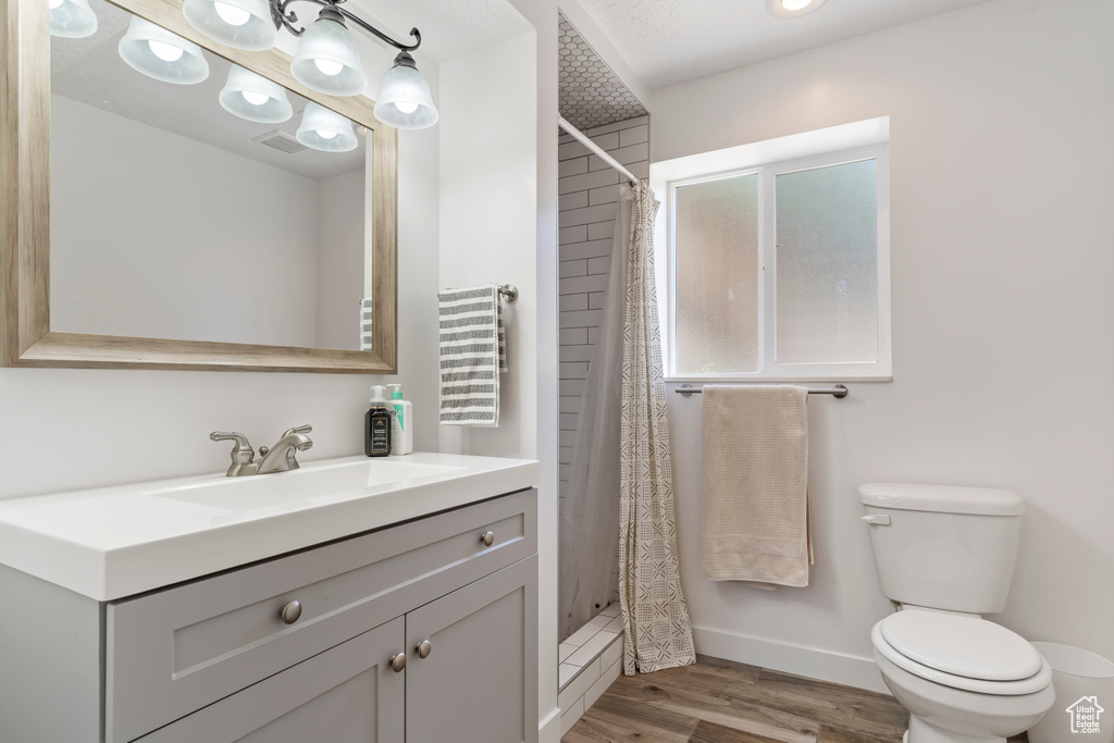 Bathroom featuring vanity, visible vents, toilet, wood finished floors, and a stall shower