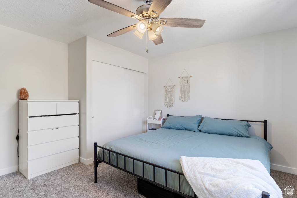 Bedroom featuring ceiling fan, a closet, light colored carpet, and baseboards