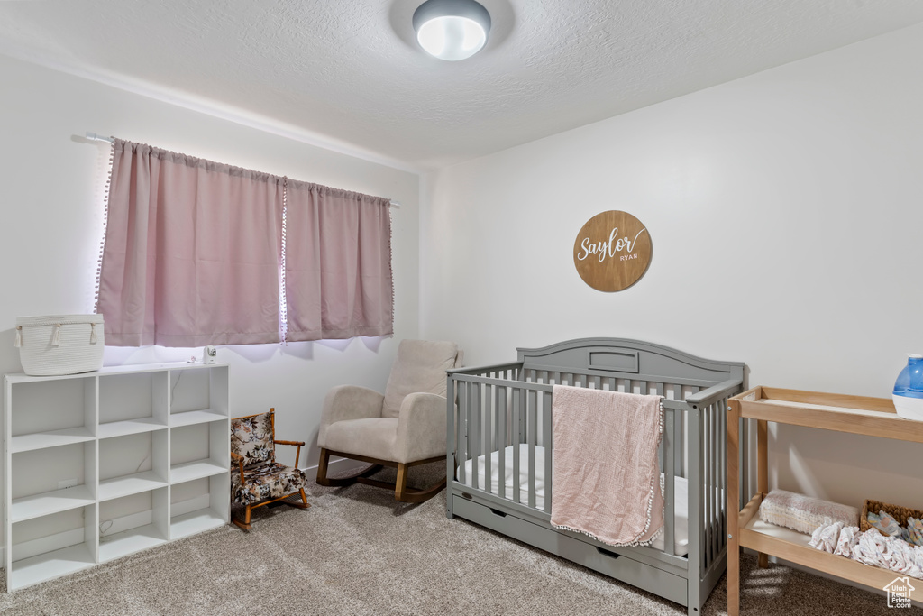 Bedroom featuring carpet flooring and a crib