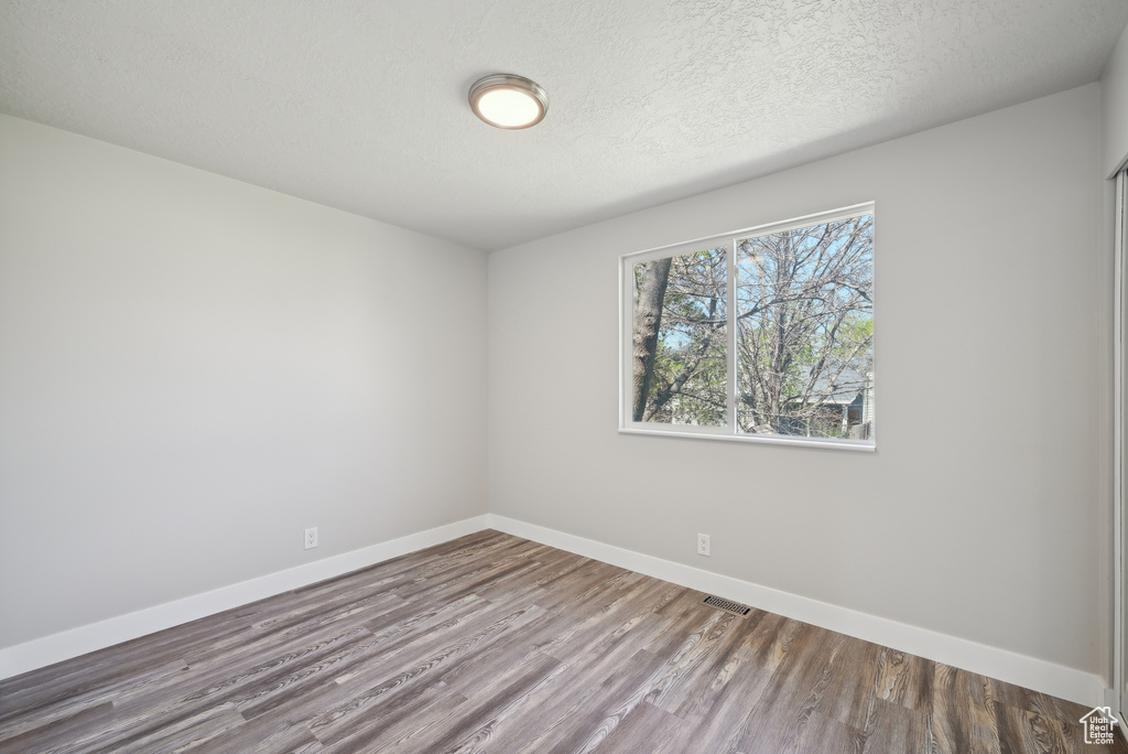 Empty room with visible vents, baseboards, wood finished floors, and a textured ceiling