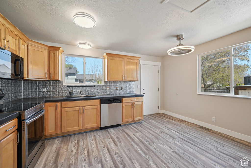 Kitchen featuring a textured ceiling, a sink, dark countertops, and stainless steel appliances