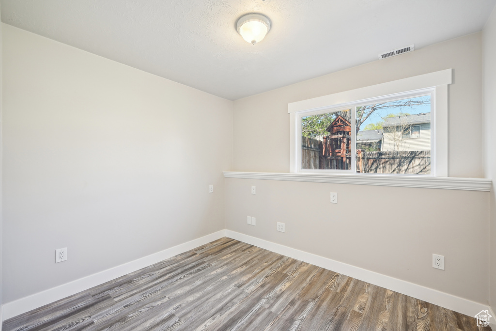 Unfurnished room with wood finished floors, baseboards, and visible vents