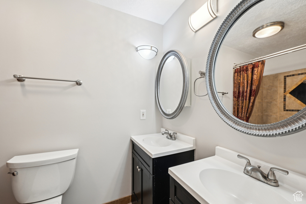 Bathroom featuring two vanities, a sink, and toilet