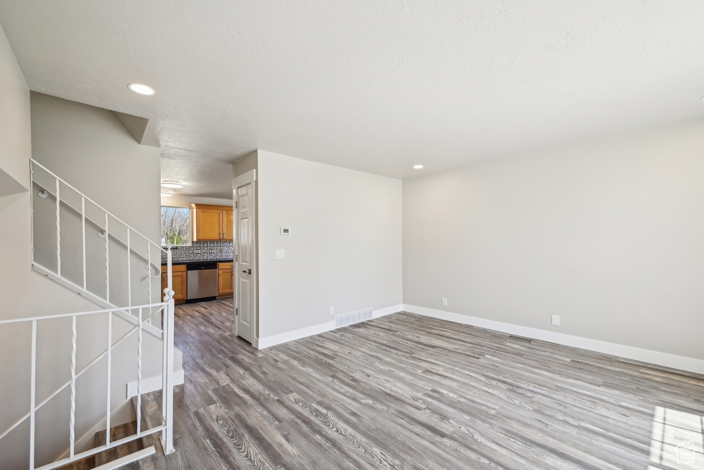 Unfurnished living room featuring baseboards, recessed lighting, stairs, visible vents, and wood finished floors