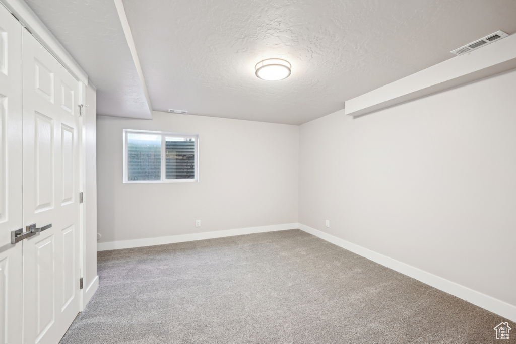 Unfurnished bedroom with visible vents, baseboards, carpet flooring, and a textured ceiling
