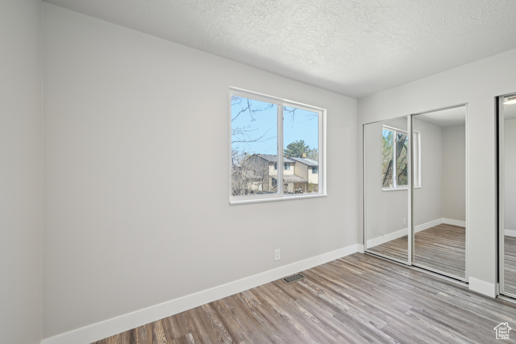 Unfurnished bedroom with visible vents, baseboards, wood finished floors, and a textured ceiling