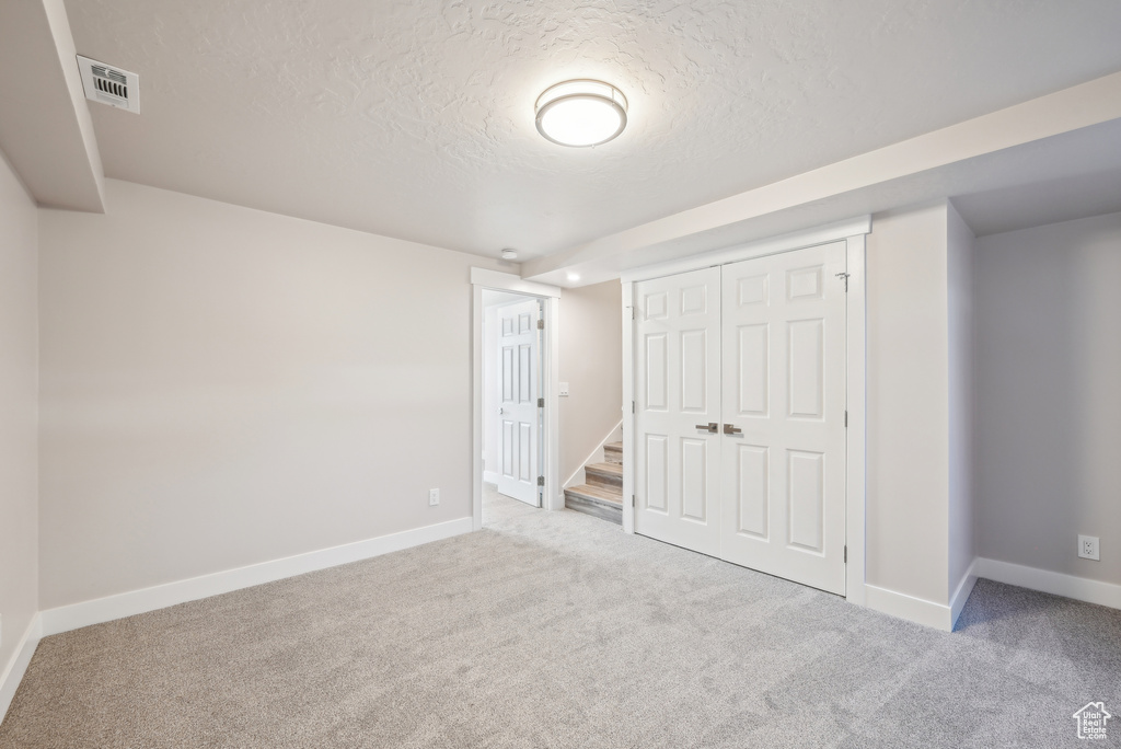 Unfurnished bedroom with visible vents, a closet, carpet, and a textured ceiling
