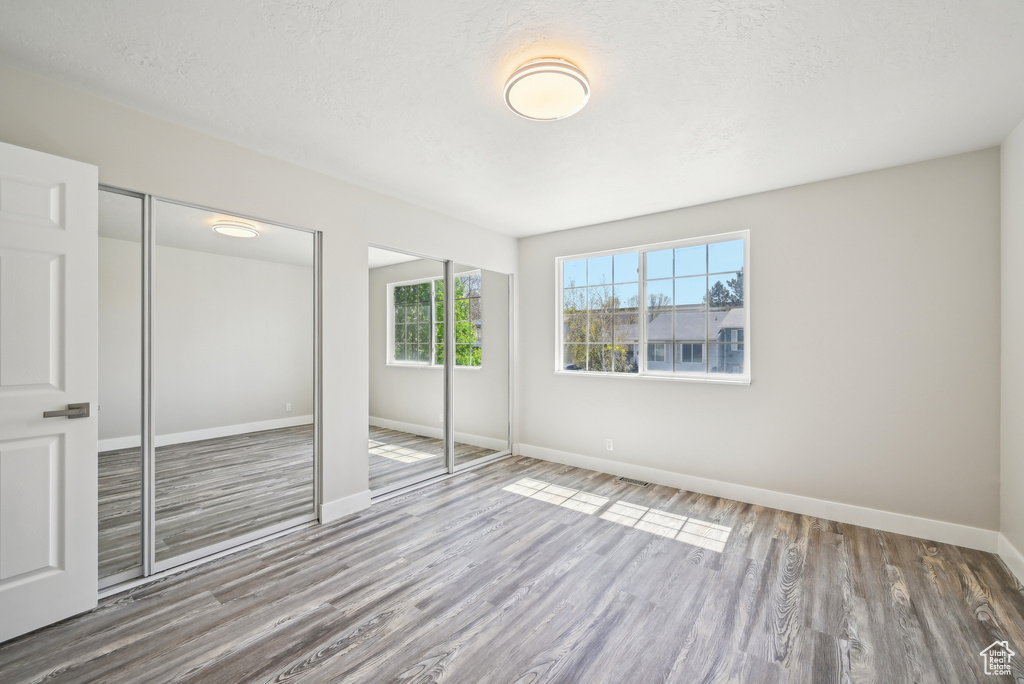 Unfurnished bedroom featuring baseboards, two closets, and wood finished floors