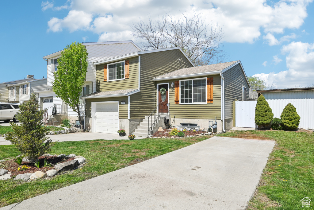 Tri-level home with a front lawn, a garage, and driveway